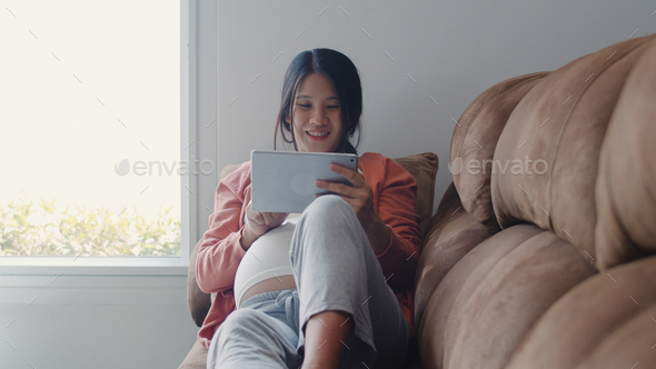 Young Asian Pregnant woman using tablet search pregnancy information. - Stock Photo - Images