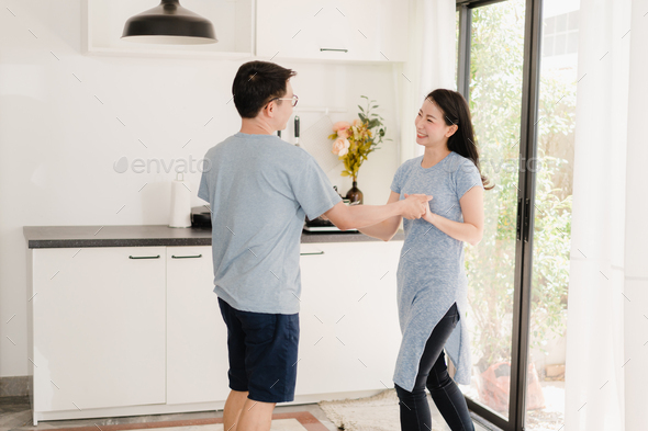 Young Asian couple listen to music and dancing after having breakfast at home.