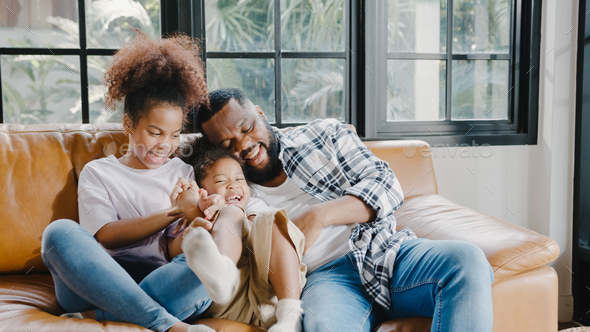 American family dad and daughter having fun cuddle play on sofa