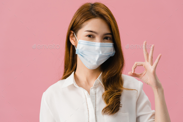 Young Asia girl wearing medical face mask gesturing ok sign with dressed in casual cloth. - Stock Photo - Images