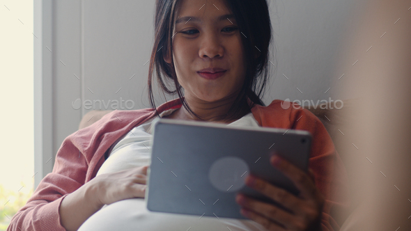 Young Asian Pregnant woman using tablet search pregnancy information. - Stock Photo - Images