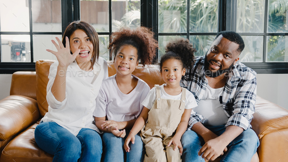 African American family having fun cuddle and video call on laptop