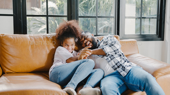 African American family having fun cuddle play on sofa while