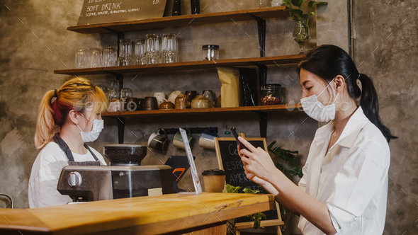 Young Asia female wear face mask self service use mobile phone pay contactless at restaurant.