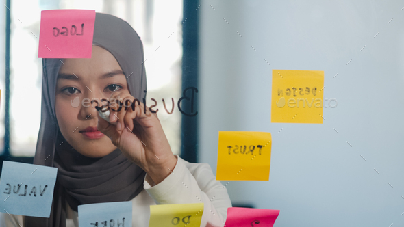 Asia muslim lady write information, strategy, reminder on glass board in new normal office.