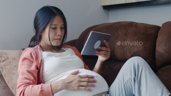Young Asian Pregnant woman using tablet search pregnancy information. - Stock Photo - Images