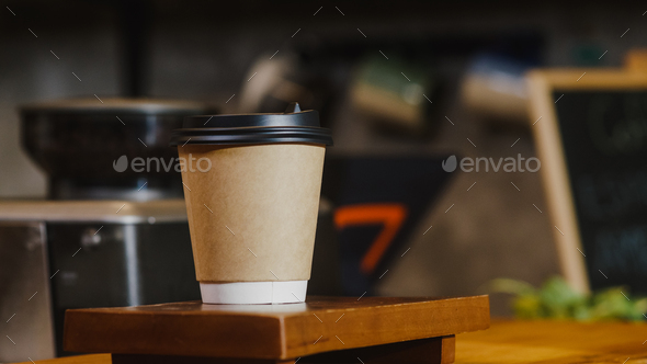 Take away hot coffee paper cup to consumer standing behind bar counter at cafe.