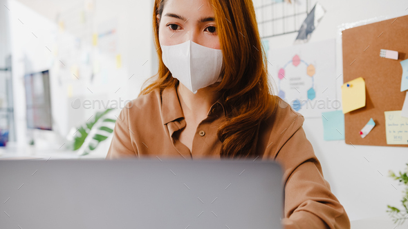 Asia businesswoman wear face mask using laptop presentation to ...