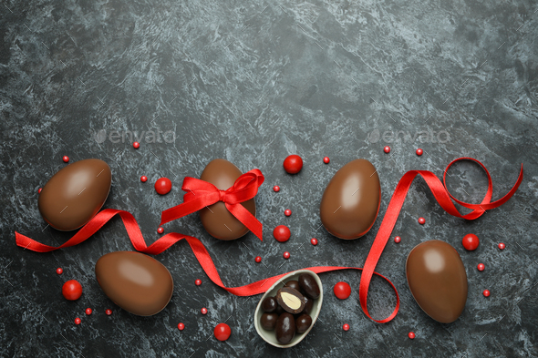 Easter chocolate eggs with candies on black smokey background