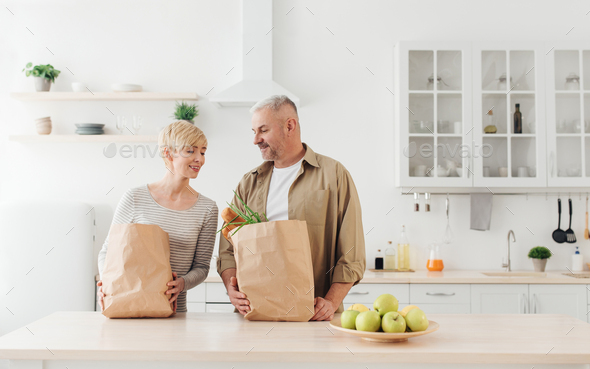 Happy family relationships, couple unpacking fresh products from market in kitchen - Stock Photo - Images