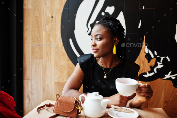 Young african woman in black blouse at cafe drink tea from teapot.