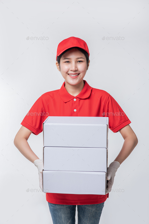 Image of young delivery man in red cap blank t-shirt uniform standing with empty white cardboard.