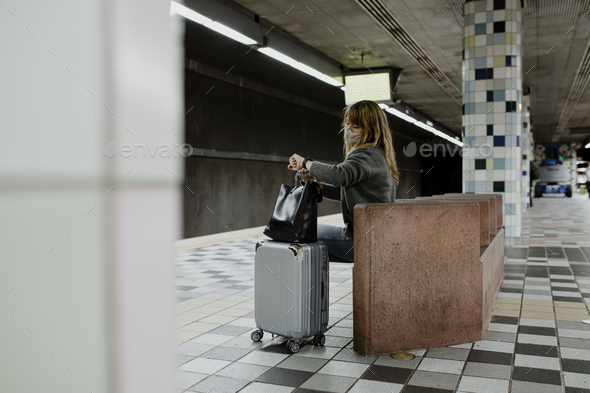 Woman looking at her watch while waiting for the train during the coronavirus pandemic