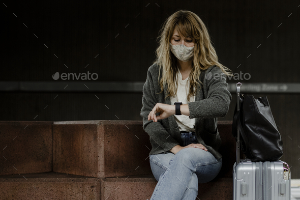 Woman looking at her watch while waiting for the train during the coronavirus pandemic