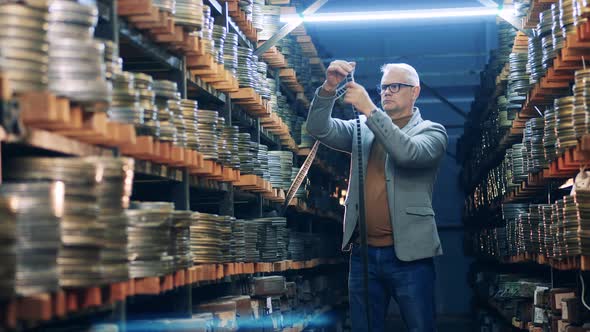 Male Specialist is Observing Antique Cinema Tapes alt