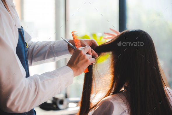 stylist cutting woman\'s hair in salon, Hairdresser coiffure trimming brown hair with scissors