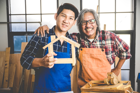 Two adult young Asian Carpenters working and designing the wooden product to build home in workshop
