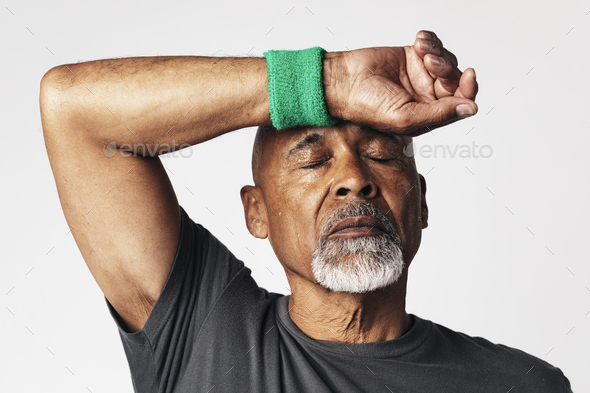 Athletic senior mean wiping off sweat from his forehead