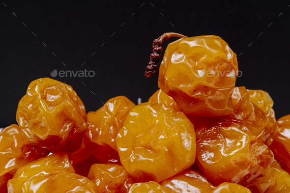 side view of dried cherry plums on black background