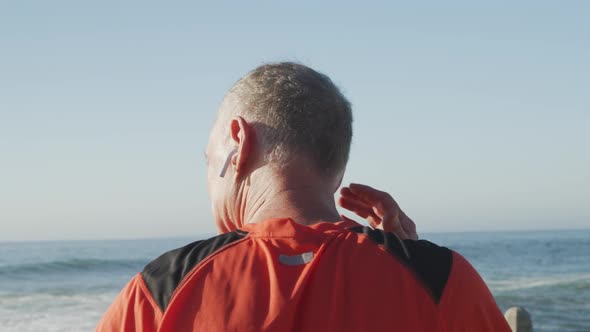 Senior man using wireless earphones while running in the park alt