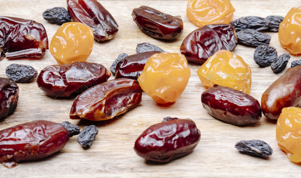 side view of dried cherry plums with raisins and dried dates scattered on sackcloth background