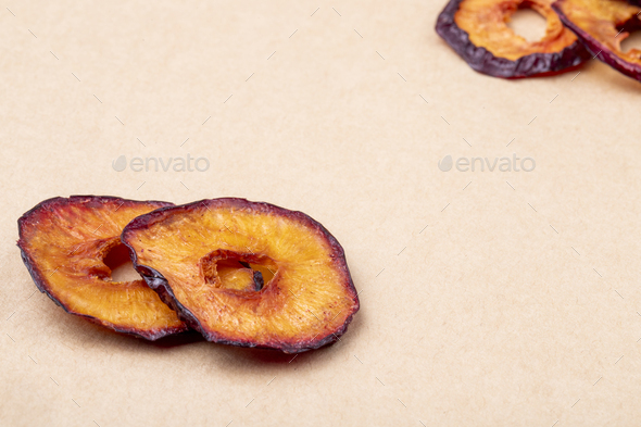 side view of dried plum slices isolated on brown paper texture background with copy space