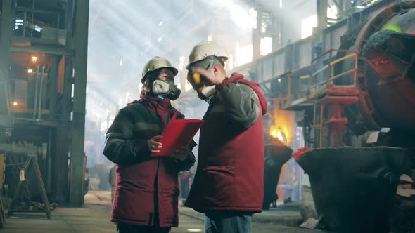 Two Steel Workers are Talking in the Metallurgical Factory Unit alt
