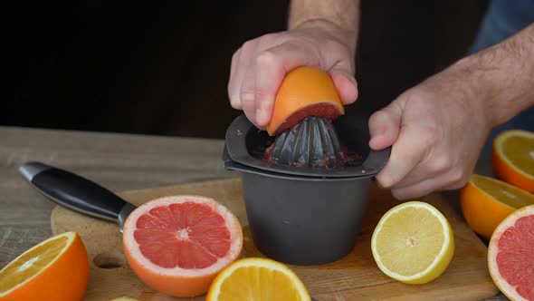 A Man Squeezes Orange Juice with Citrus Juicer alt
