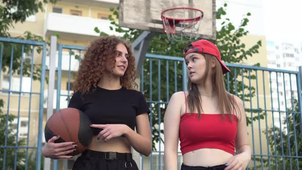 Two Young Sports Women Teenagers with a Basketball Ball Outdoors alt