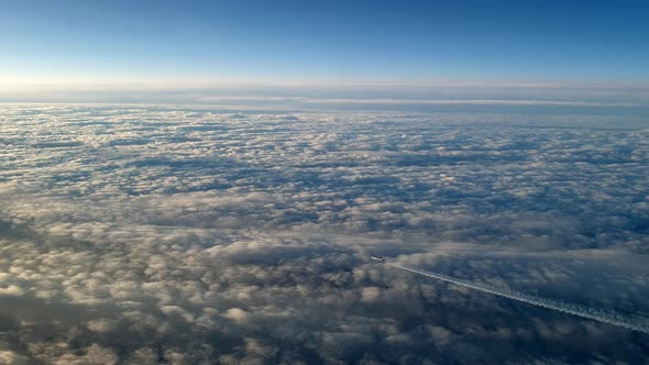 Incredible view from the cockpit of an airplane flying high above the clouds leaving a long white co alt