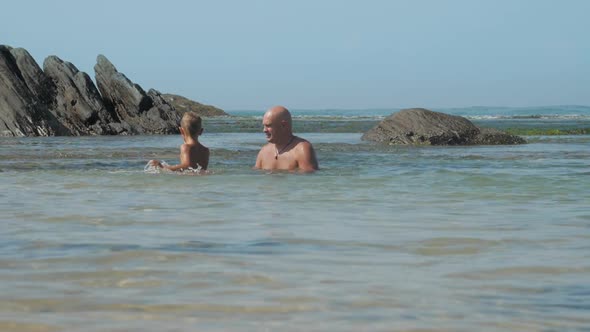 Happy Man Spends Time with Little Son in Azure Sea Bay alt