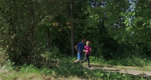 Couple Jogging on a Country Road Through the Beautiful Sunny Forest alt