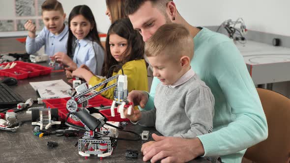 Young Father and Son are Testing a Crane Constructor at a Robotics School Having Fun and Laughing