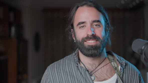 Young Bearded Man Standing Close to a Microphone Looking at the Camera alt
