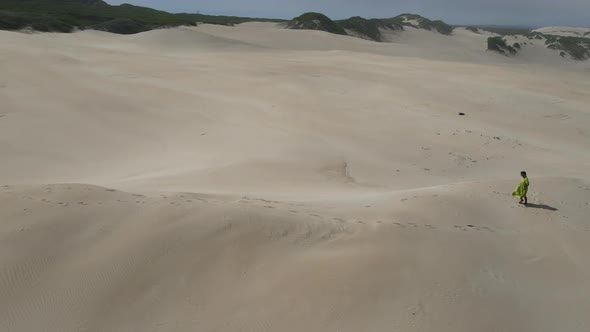 Drone View of Woman Walking Along Sand Dune