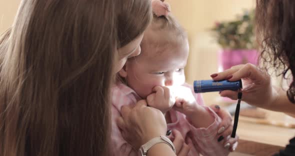 Young Woman Showing Her Little Scared Kid to Pediatrician