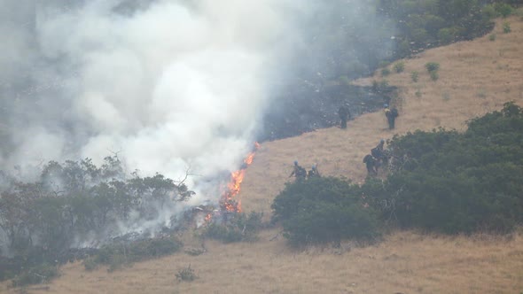 Wildfire burning on mountain as firefighters control the blaze alt