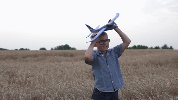 Happy guy with a toy airplane on a wheat field in the sunset light. alt