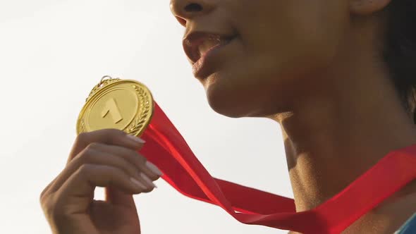 Happy mixed-race sportswoman smiling and rejoicing victory and gold medal alt