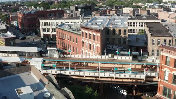 A slow, daytime, aerial cinematic reveal of a cityscape skyline behind a rail train station in Chica alt