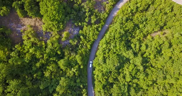 Aerial drone view of a minivan car vehicle driving on a rural road alt