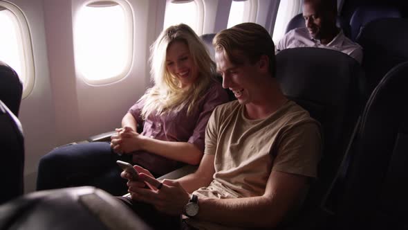 Couple looking at mobile phone together on airplane flight
