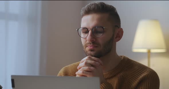 Young Man with Glasses Is Listening and Viewing Lecture or Speech of Participant of Online Meeting alt