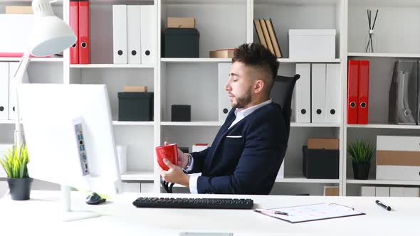 Young Businessman Drinking Coffee at Workplace