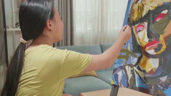 Asian Artist Girl In Wheelchair Holding Paintbrush And Painting A Girl's Face On The Canvas alt