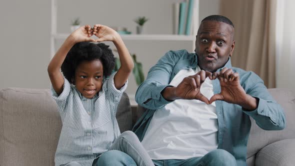 Happy Funny African American Family Mature Father and Little Daughter Sitting on Sofa in Room alt
