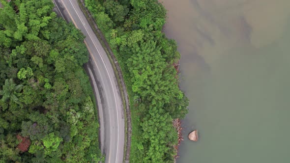 Aerial birdseye flying over riverside road, Brazil. Showing jungle, street and sea. alt