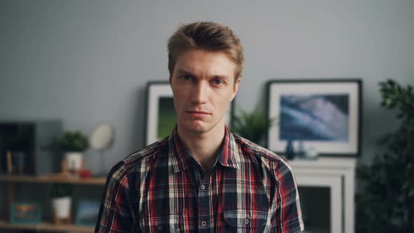 Portrait of Handsome Young Man Looking at Camera with Unhappy Face Wearing Bright Checkered Shirt alt