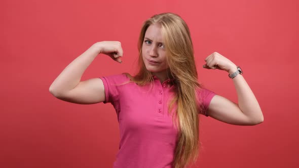 Young Woman Points To the Strong Hands on a Red Background alt