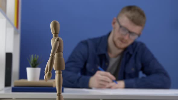 Young Architect in Glasses Designs a Wooden Gestalt Figure. The Creative Process alt